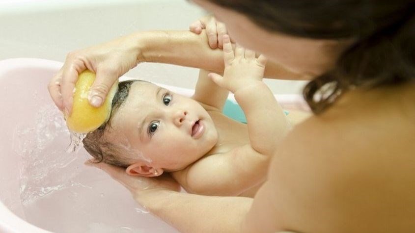 Khi tắm bé sơ sinh, mẹ nên gội đầu cho bé bằng khăn thấm nước vừa phải go1care